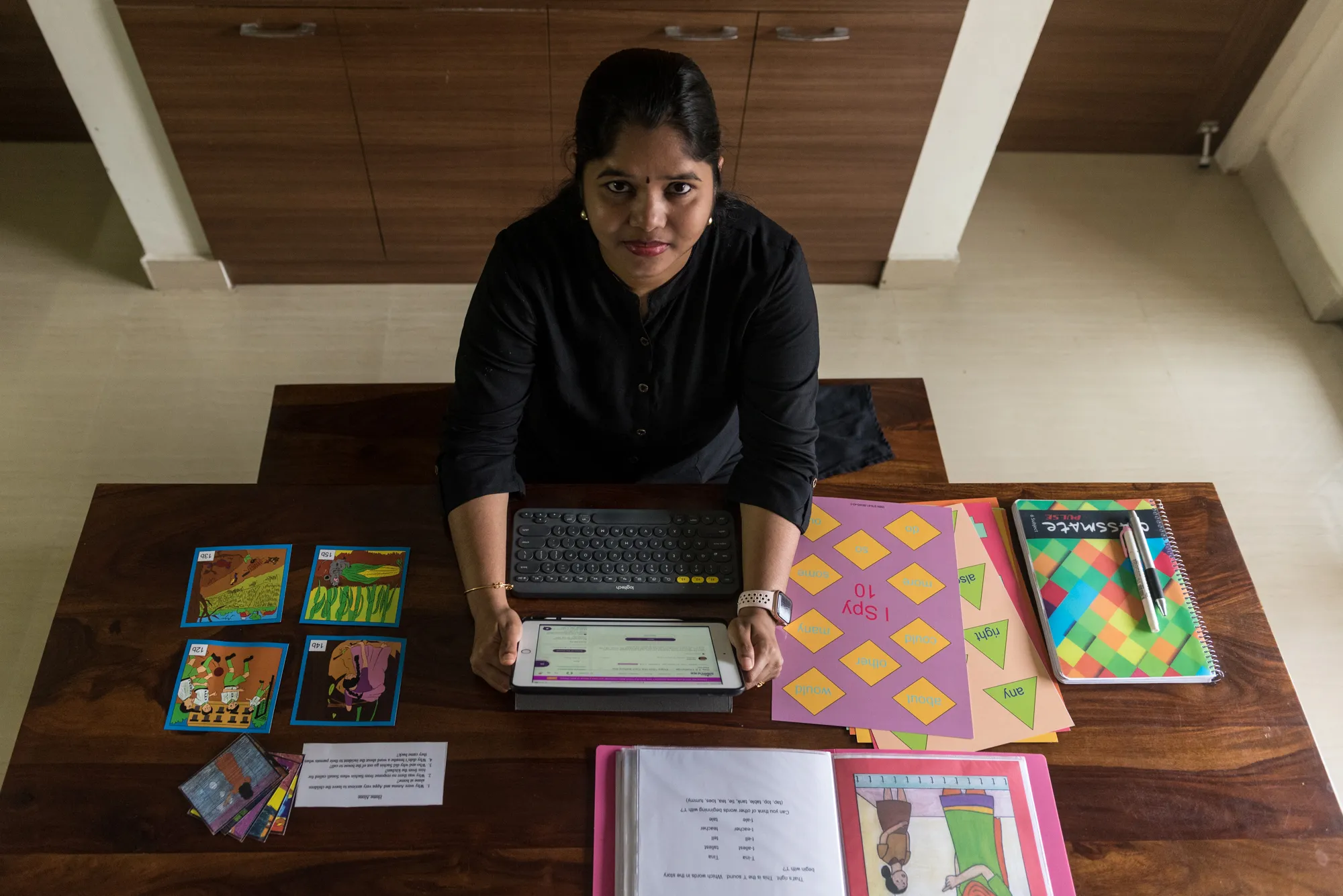 Dr. Gayathri at her teaching desk with phonics cards, word games, and reading materials prepared for a session